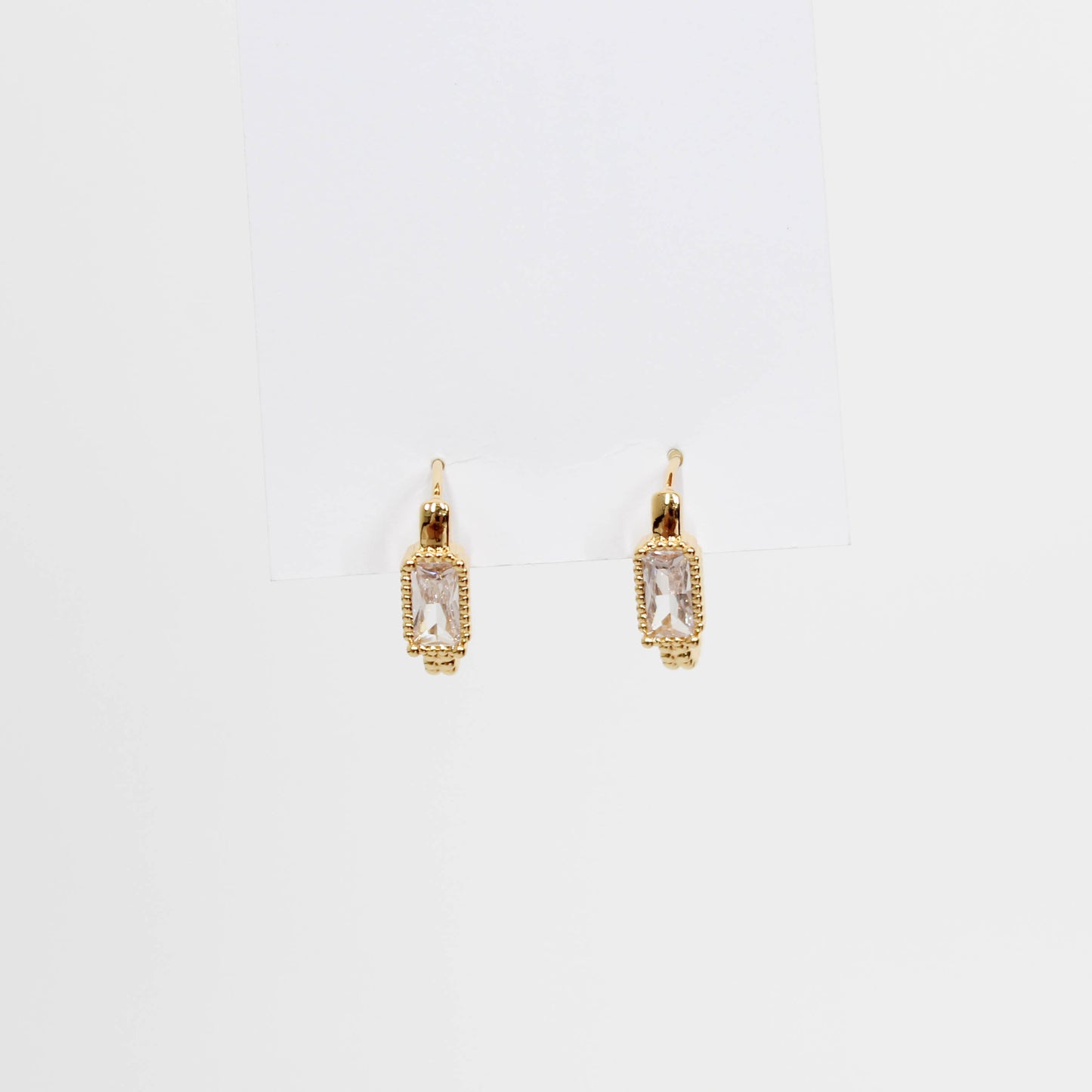 Gold hoop earrings with clear gemstones baguette oblong huggies on a white background