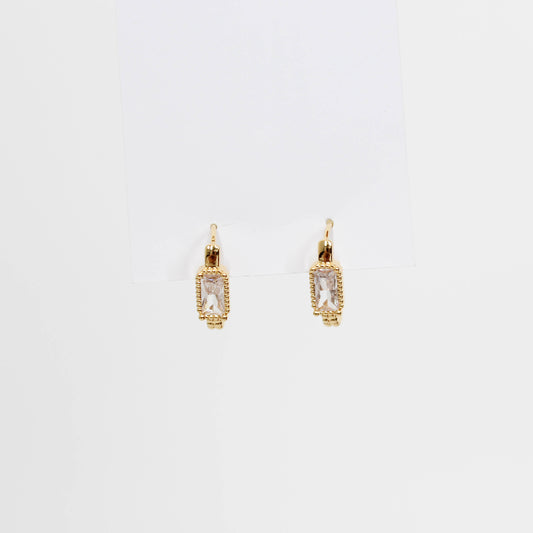 Gold hoop earrings with clear gemstones baguette oblong huggies on a white background