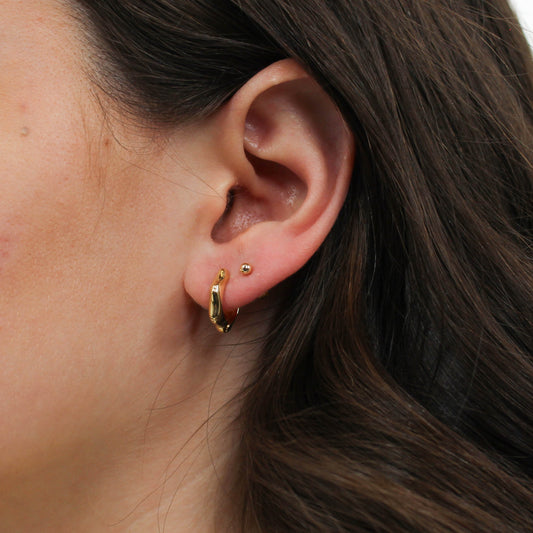 Close-up gold bamboo hoop earrings.