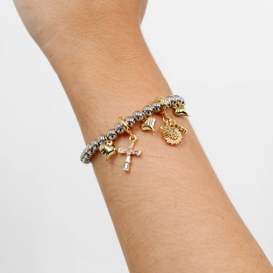 Beaded bracelet with various charms including a cross charm on a wrist against a white background