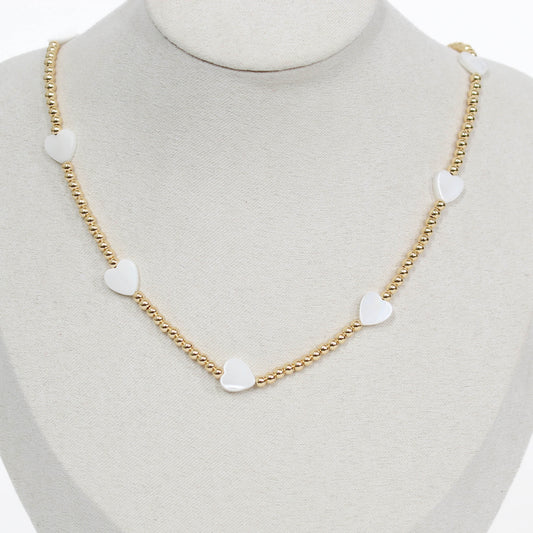 Gold chain beaded necklace with heart-shaped white pendants on a mannequin.