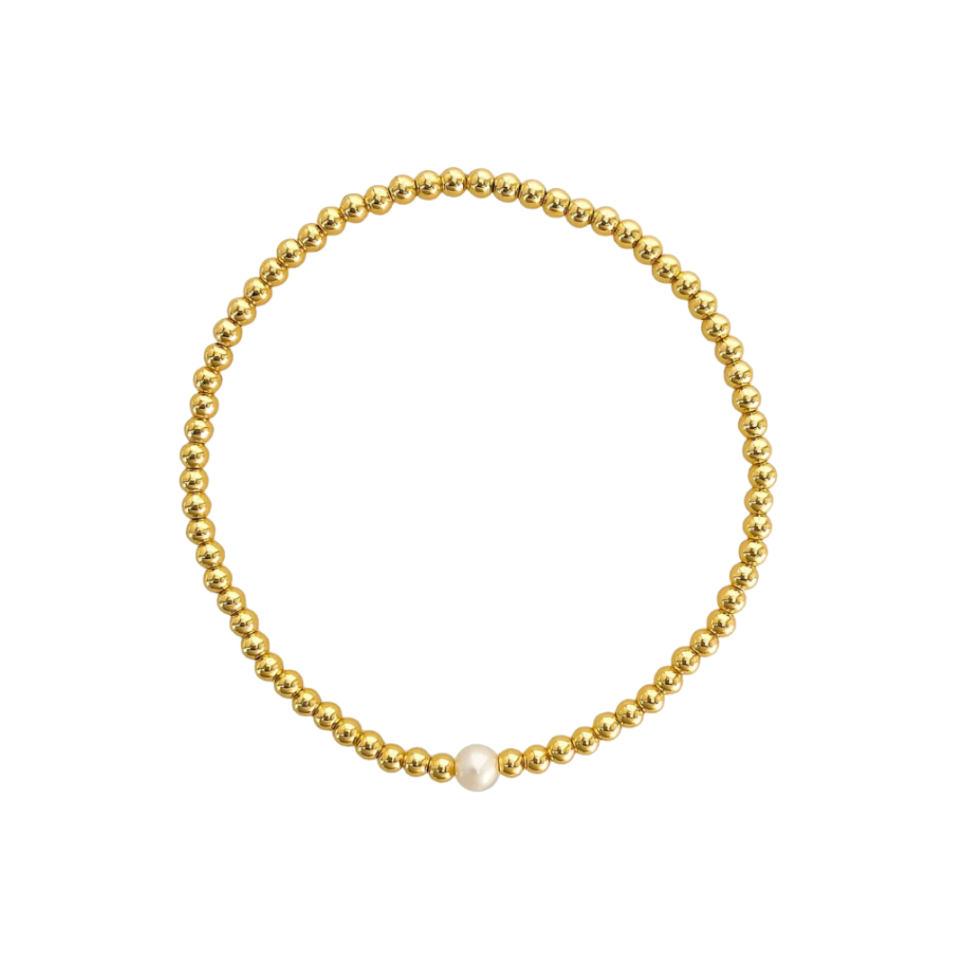 Gold beaded bracelet with a single white pearl on a white background