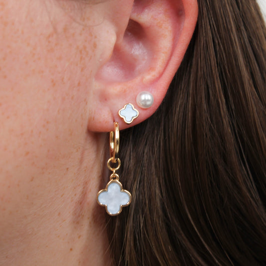 Close-up of an ear with gold clover earring set in white