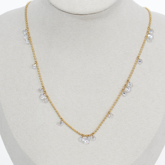 Gold necklace with clear drop crystal stones on a mannequin bust against a white background