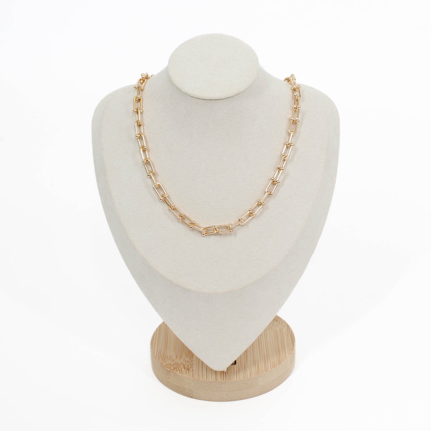Gold chain hardware necklace on a white mannequin bust with a wooden base