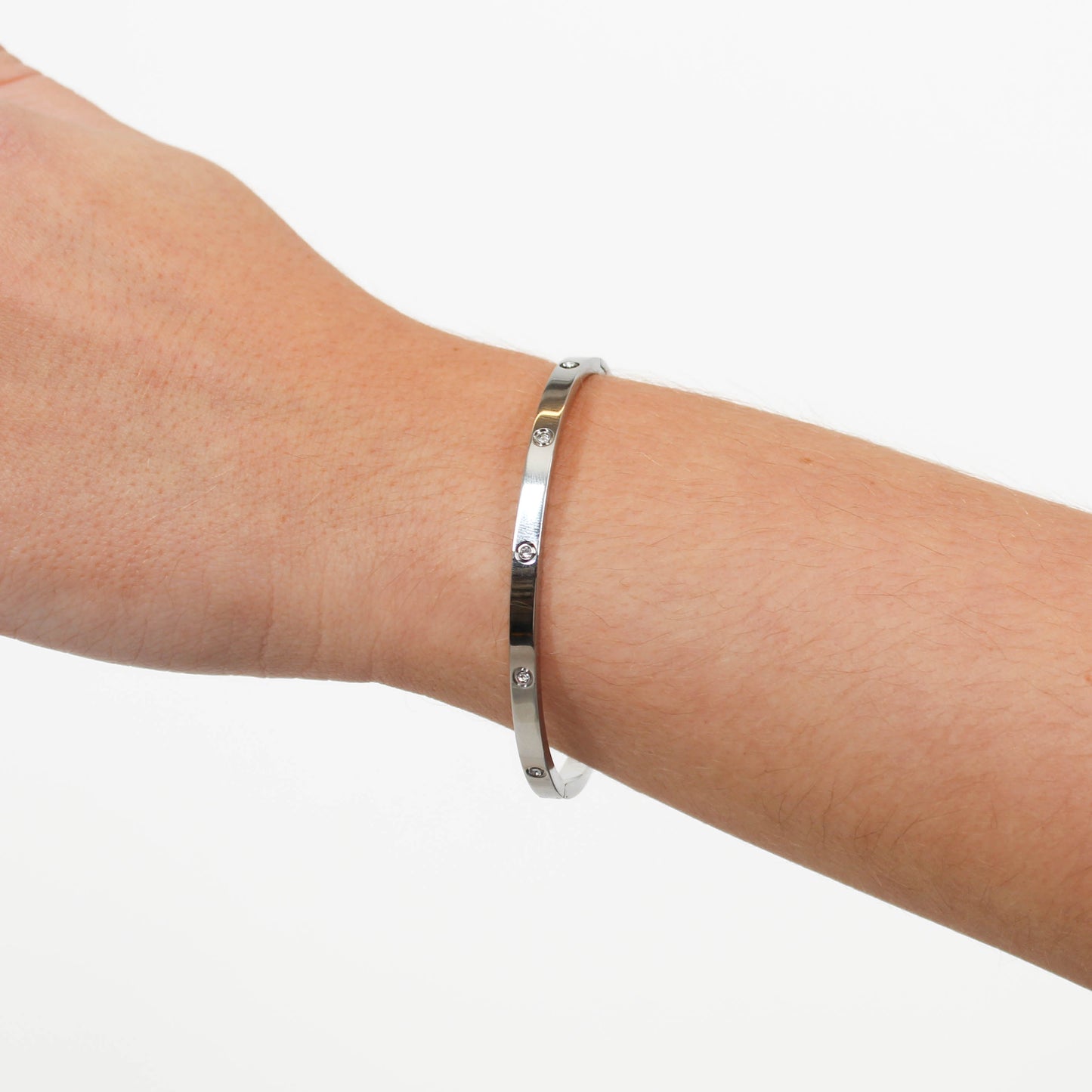 Silver bracelet on a person's wrist against a white background