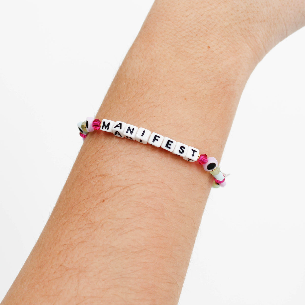 Little Words Project bracelet with 'MANIFEST' beads on a wrist against a white background