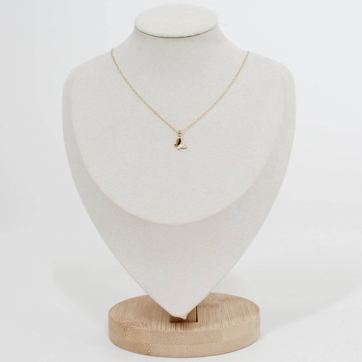 Gold necklace with a small butterfly pendant on a white mannequin bust.