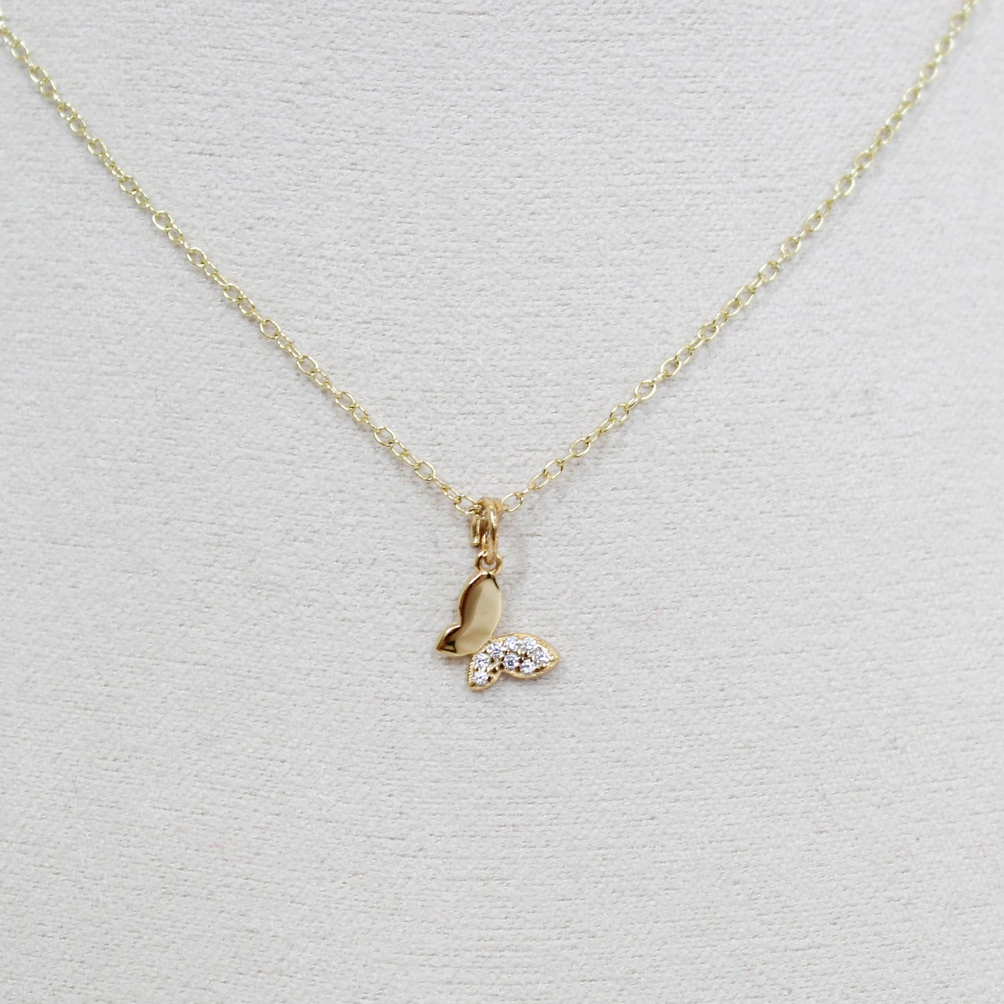 Gold butterfly necklace with a small pendant on a white background
