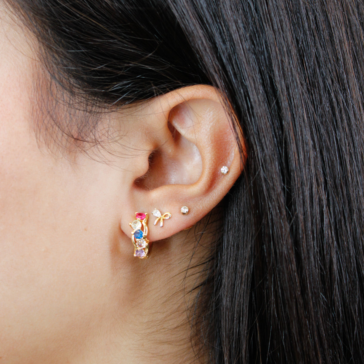 Close up of Multicolor Cluster Huggie Earrings on a model