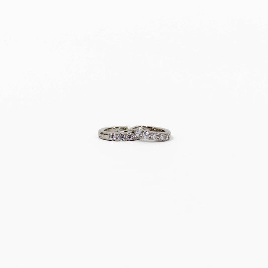 Silver pave huggie earrings with embedded stones on a white background