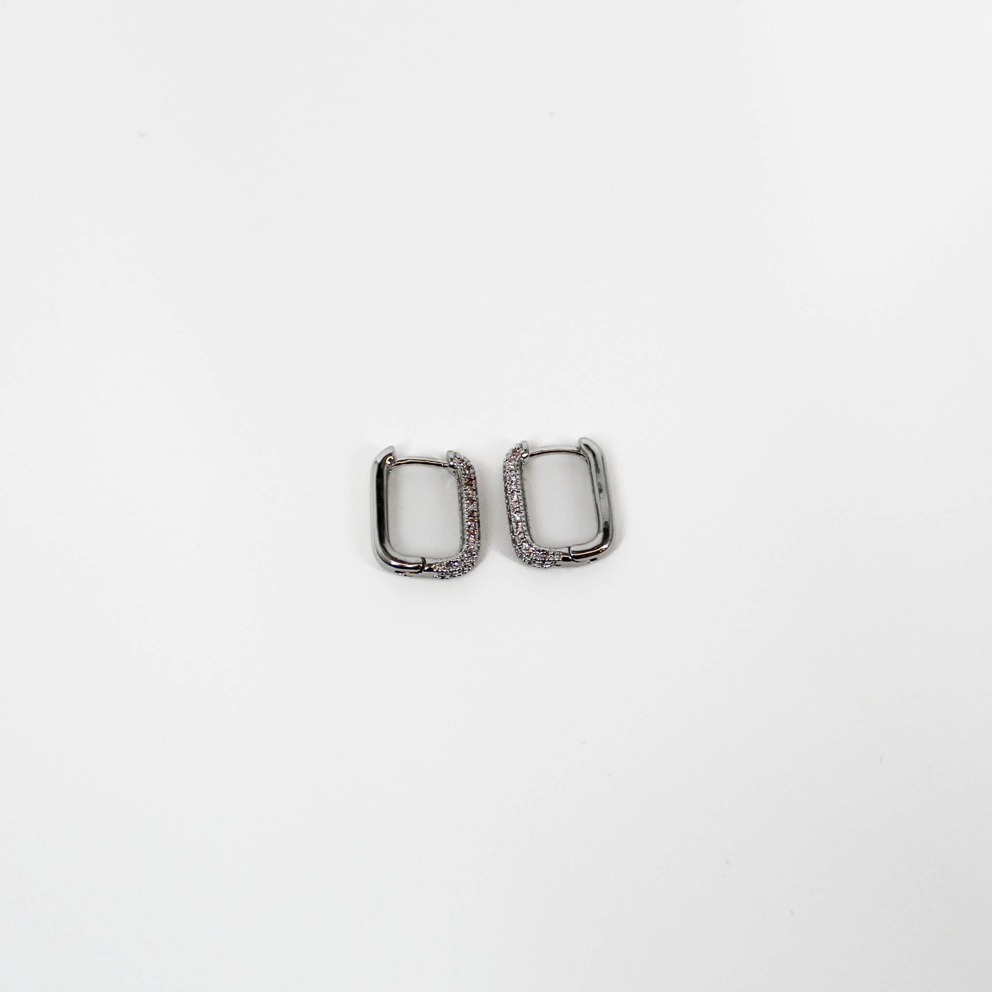Two silver square huggie hoop earrings on a white background