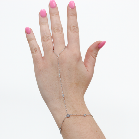 Hand wearing a silver stone charm hand chain bracelet on a white background