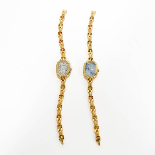 Gold chain vintage oval watches with white and blue clock faces on a white background