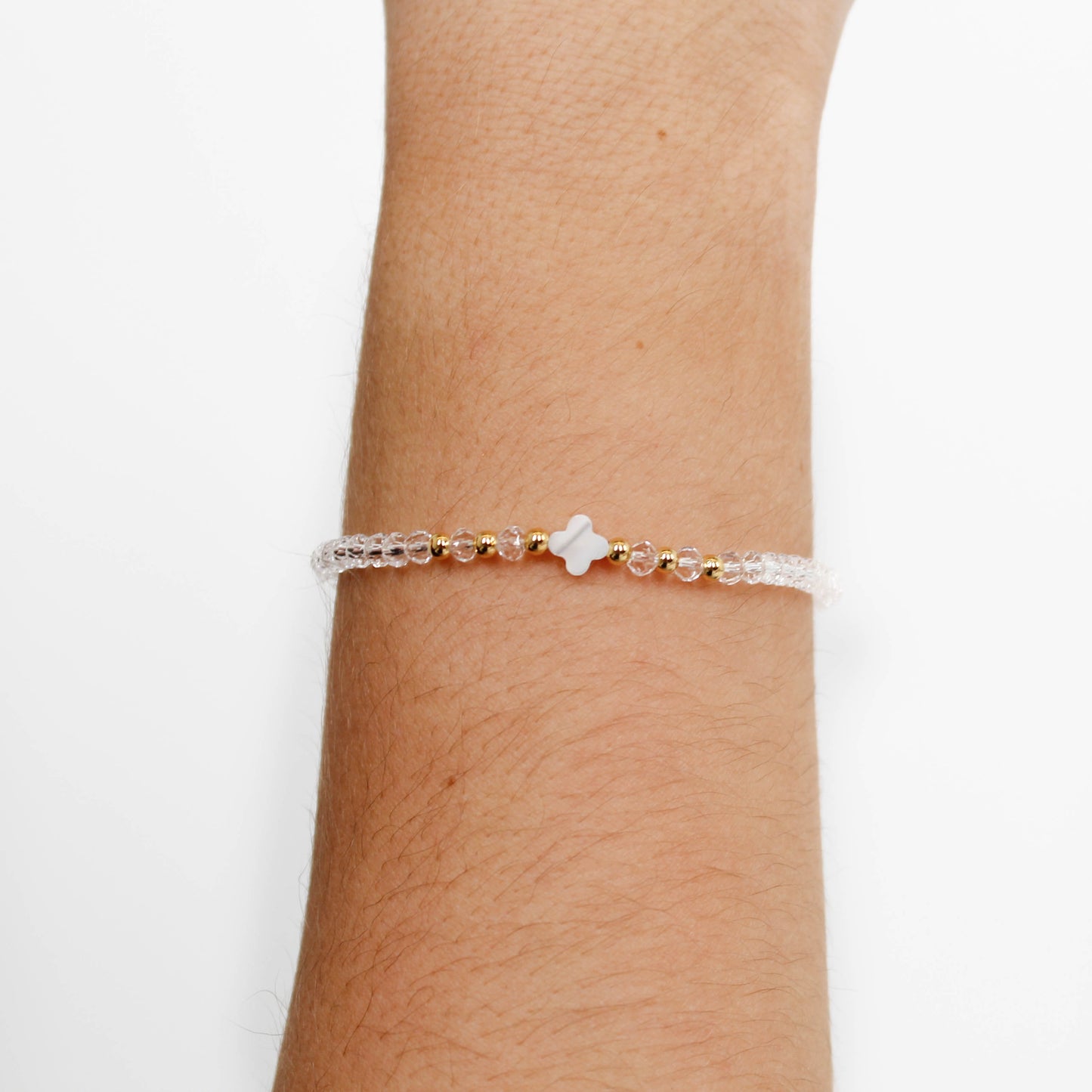 clear crystal clover bracelet with a star charm on a wrist against a white background