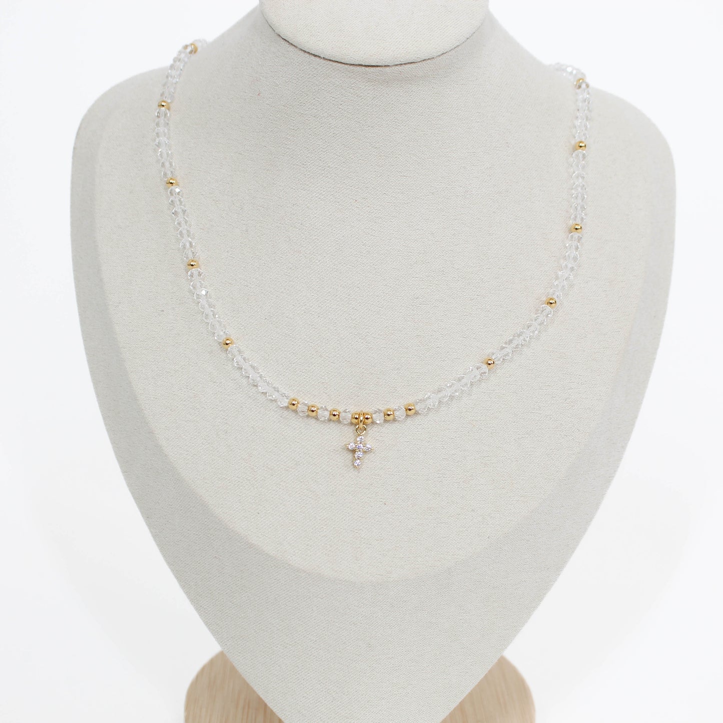 mini cross choker Necklace in clear with gold beads and a cross pendant on a mannequin bust.