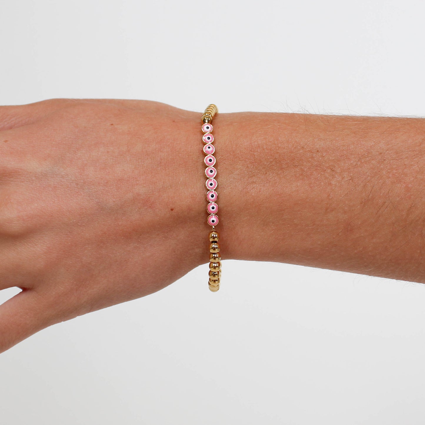 Bracelet with pink and gold beads on a wrist against a white background