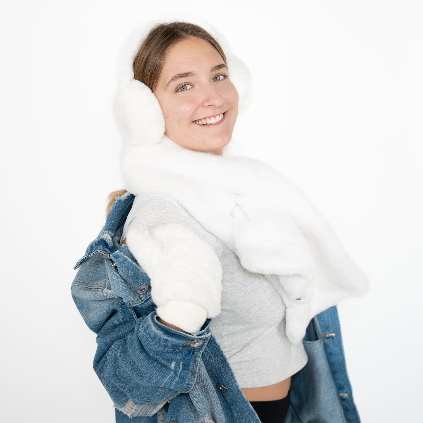 white fuzzy scarf on and matching gloves and earmuffs