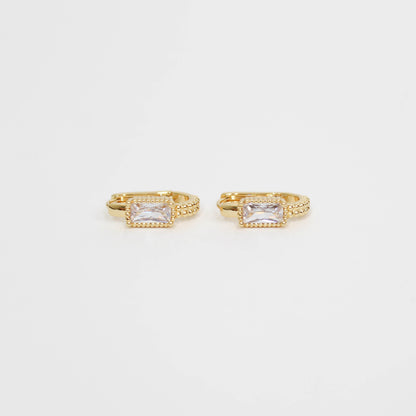 Gold hoop earrings with clear gemstones baguette oblong huggies on a white background