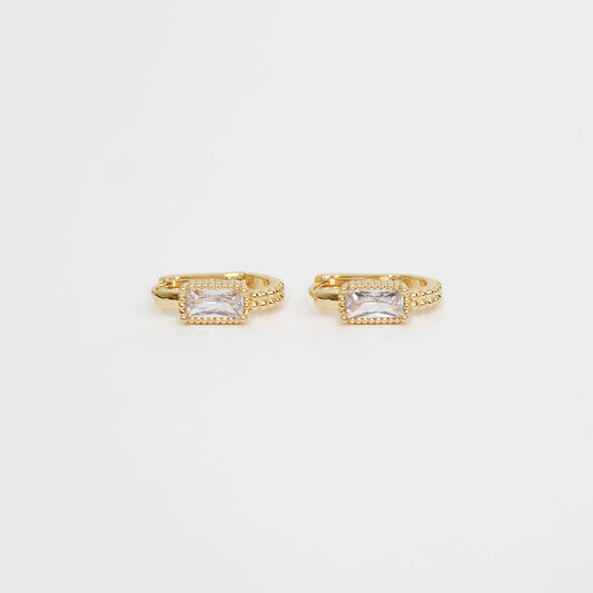 Gold hoop earrings with clear gemstones baguette oblong huggies on a white background