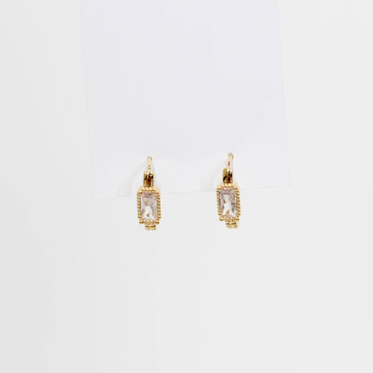 Gold hoop earrings with clear gemstones baguette oblong huggies on a white background