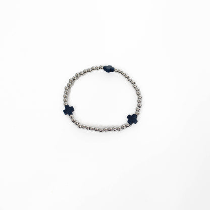 Bracelet with silver beads on a white background and black cross accents. 