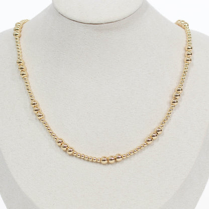 Gold beaded necklace on a mannequin with a white background