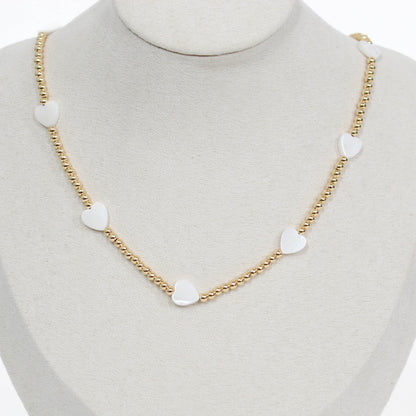 Gold chain beaded necklace with heart-shaped white pendants on a mannequin.