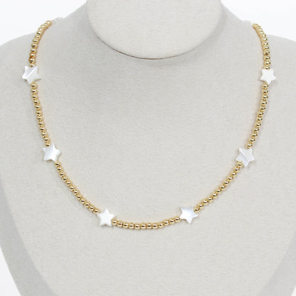 Gold beaded icon necklace with star-shaped pendants on a mannequin