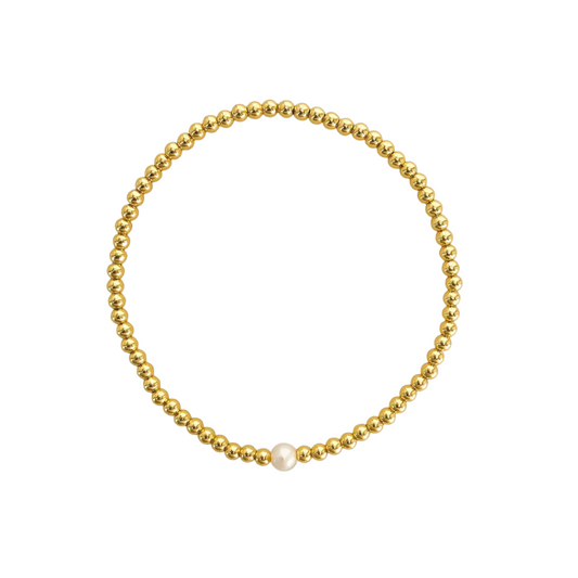 Gold beaded bracelet with a single white pearl on a white background