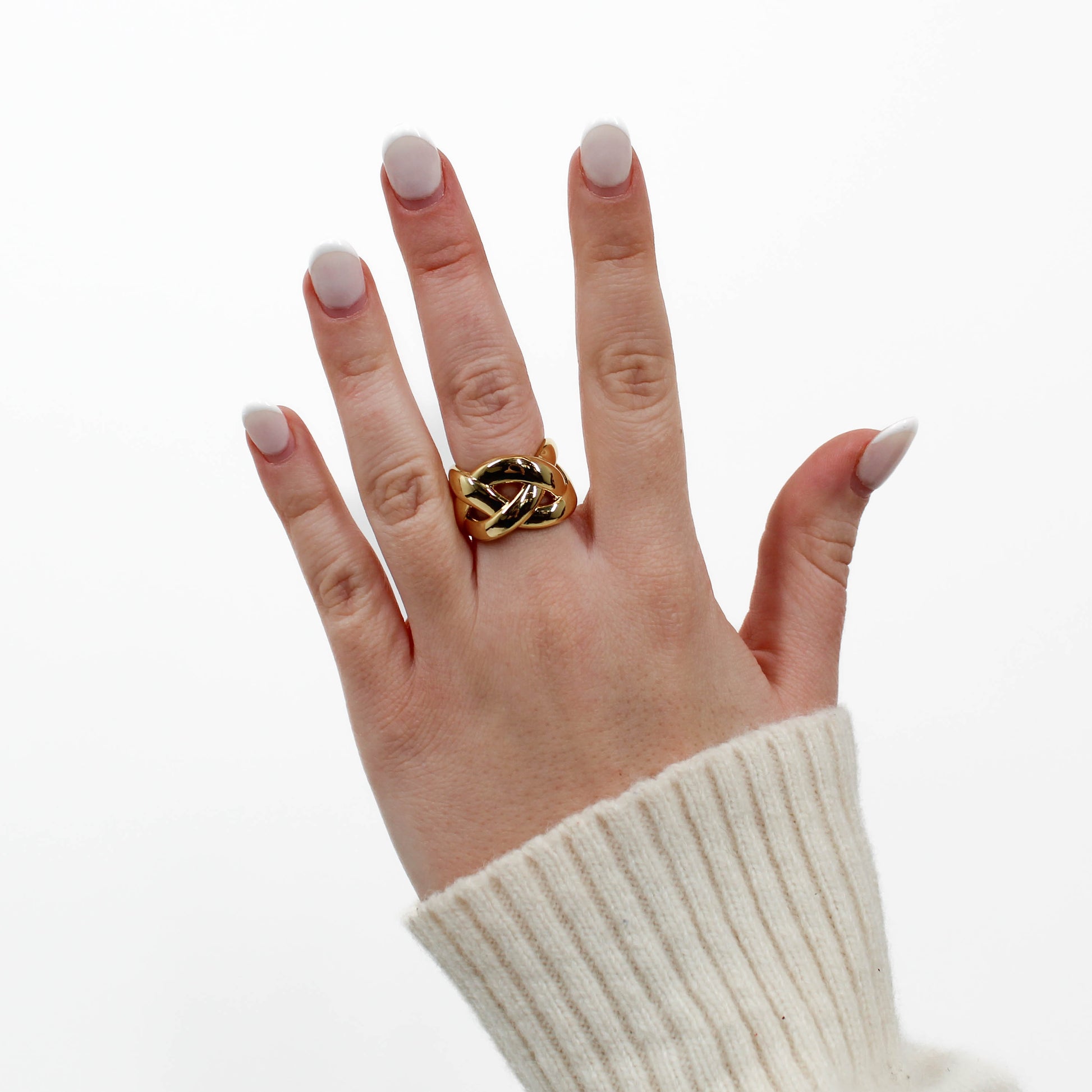 Hand wearing a gold braided band ring on a white background