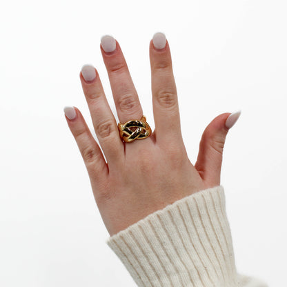 Hand wearing a gold braided band ring on a white background