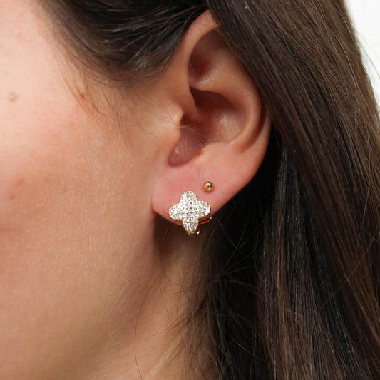 Gold crystal clover huggie earrings on ear