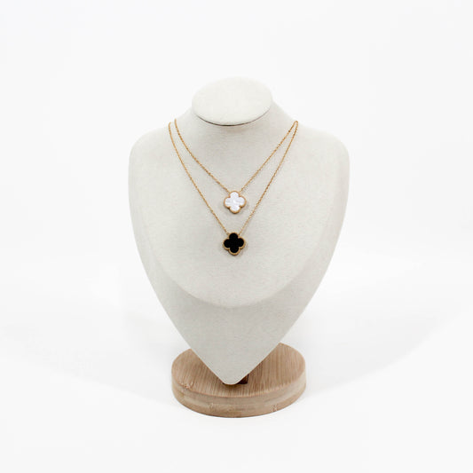 Two gold clover pendant necklaces on a white mannequin bust with a white background