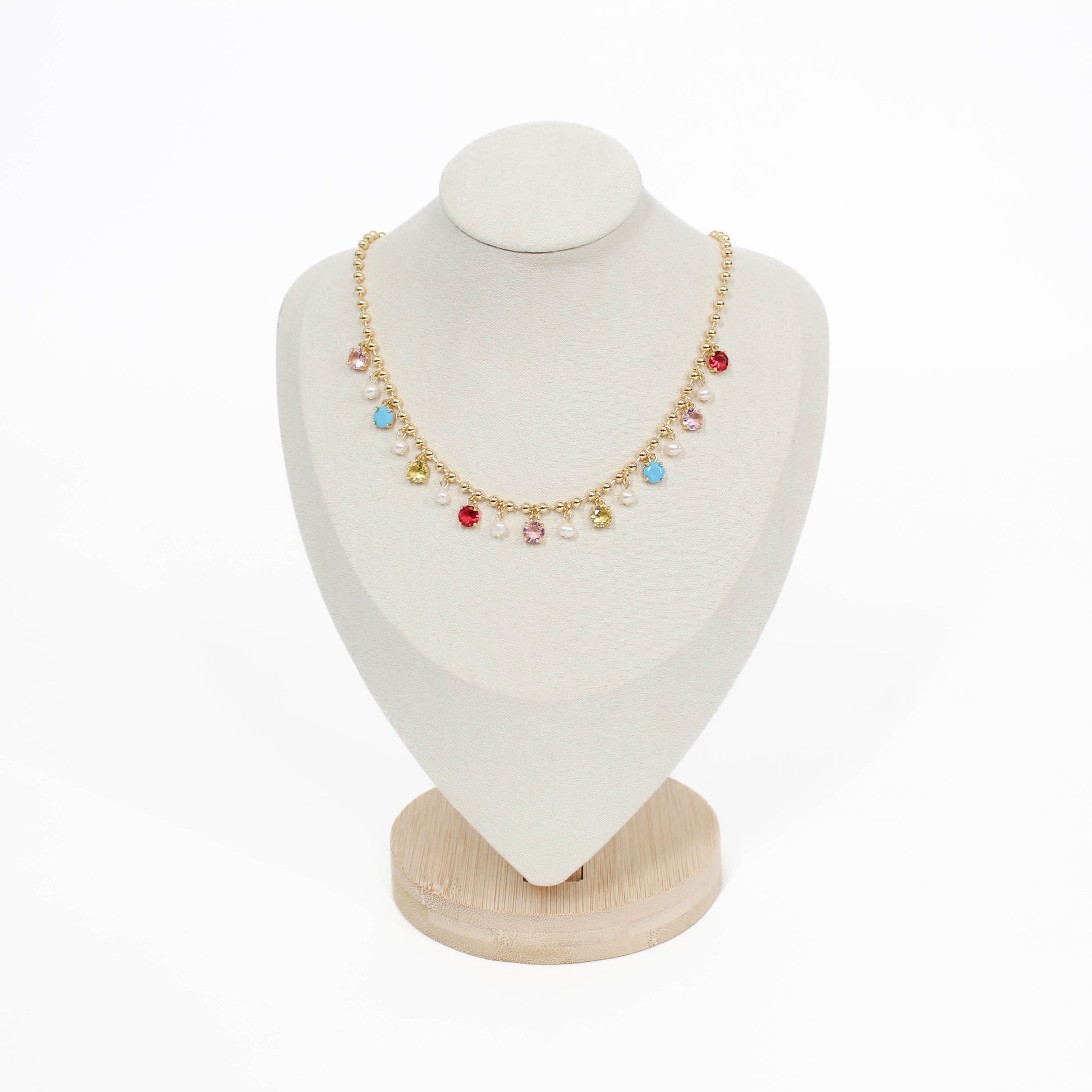 Necklace with colorful beads on a white bust with a wooden base