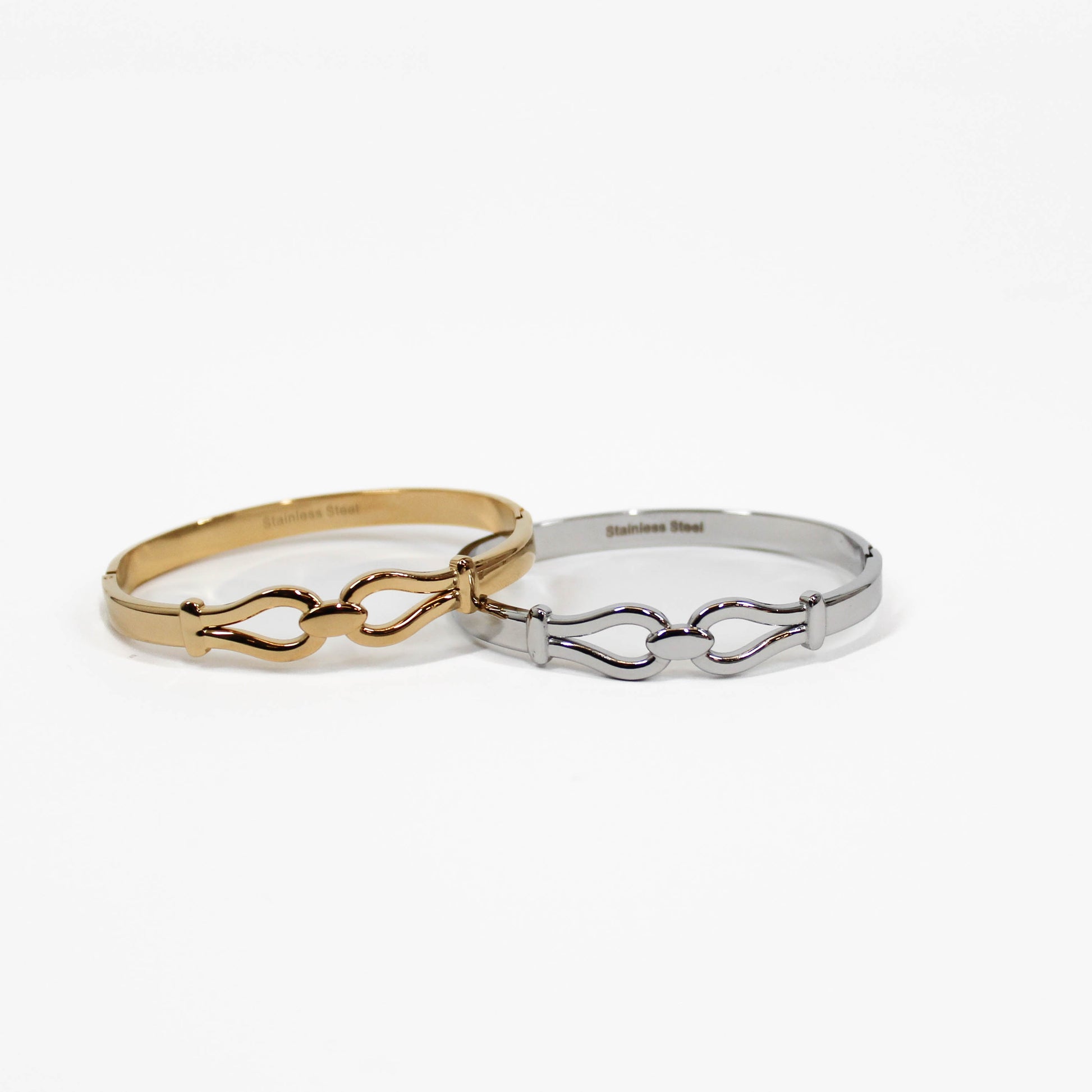 Two double link bangles one gold and one silver, on a white background