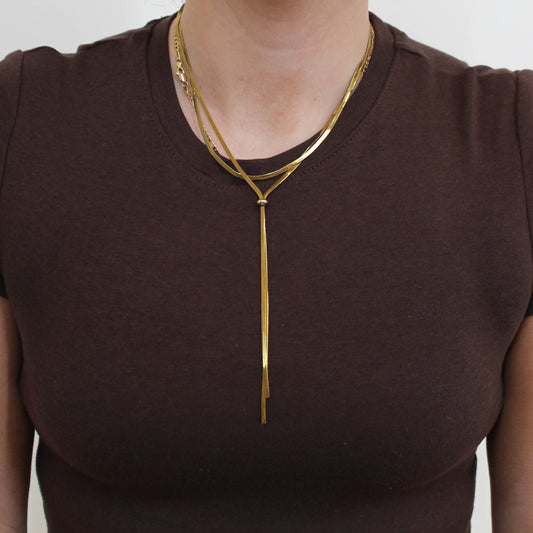 Person wearing a gold double loop lariat necklace 
