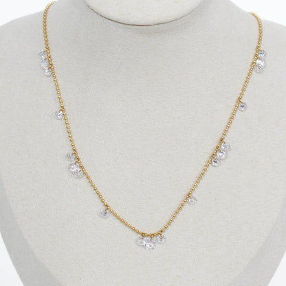 Gold necklace with clear drop crystal stones on a mannequin bust against a white background