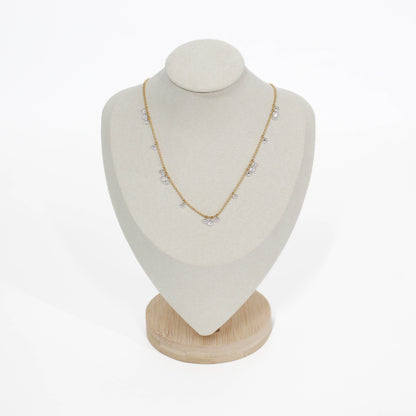 Gold drop crystal necklace on a white mannequin bust with a wooden base against a white background