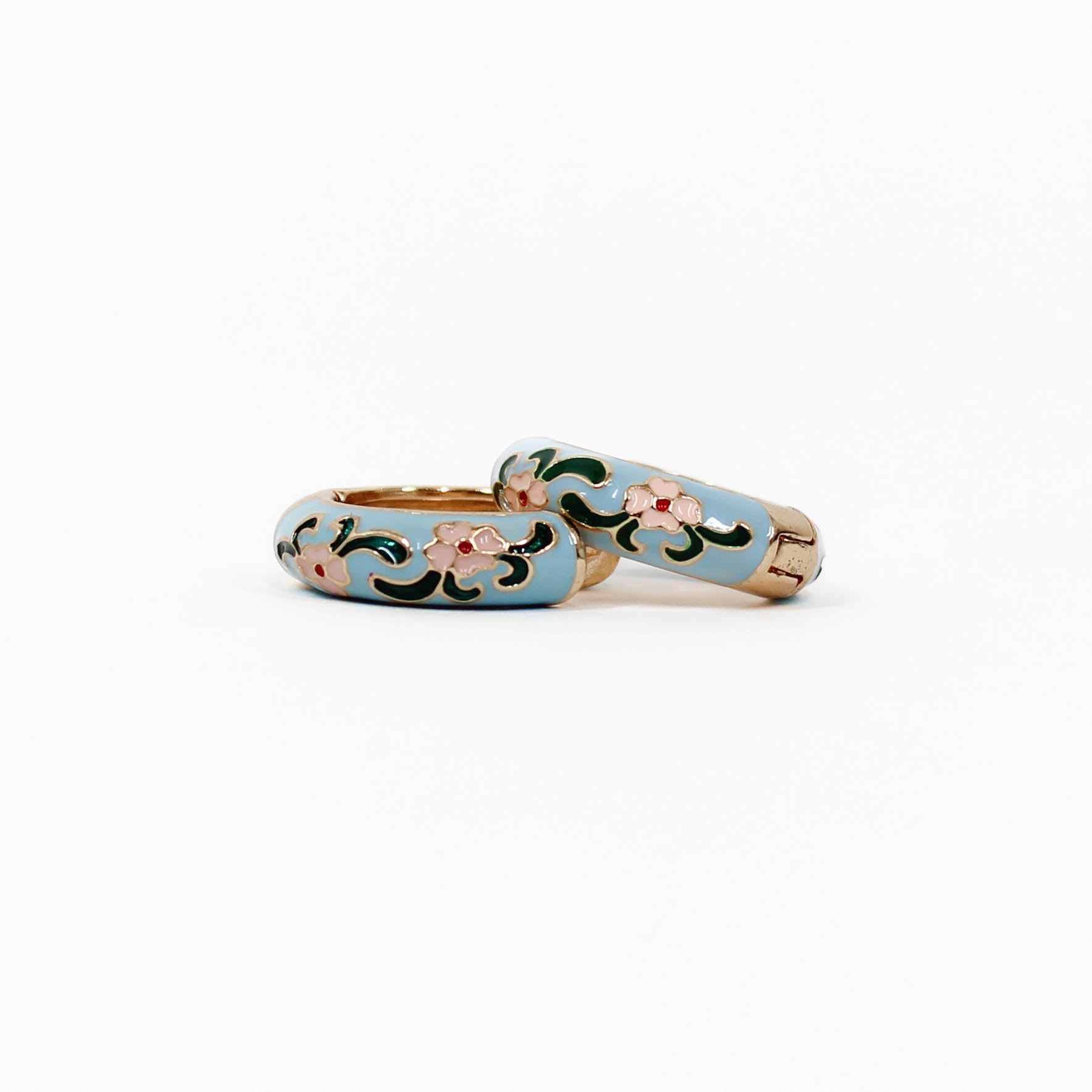 pair of floral huggie earrings in blue on a white background