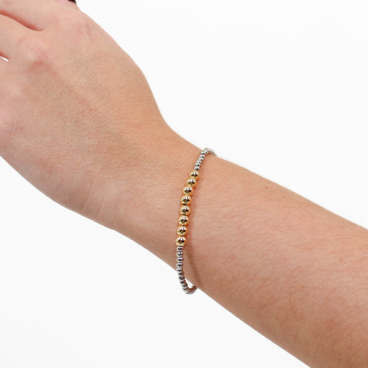 Silver and Gold beaded bracelet on a wrist against a white background