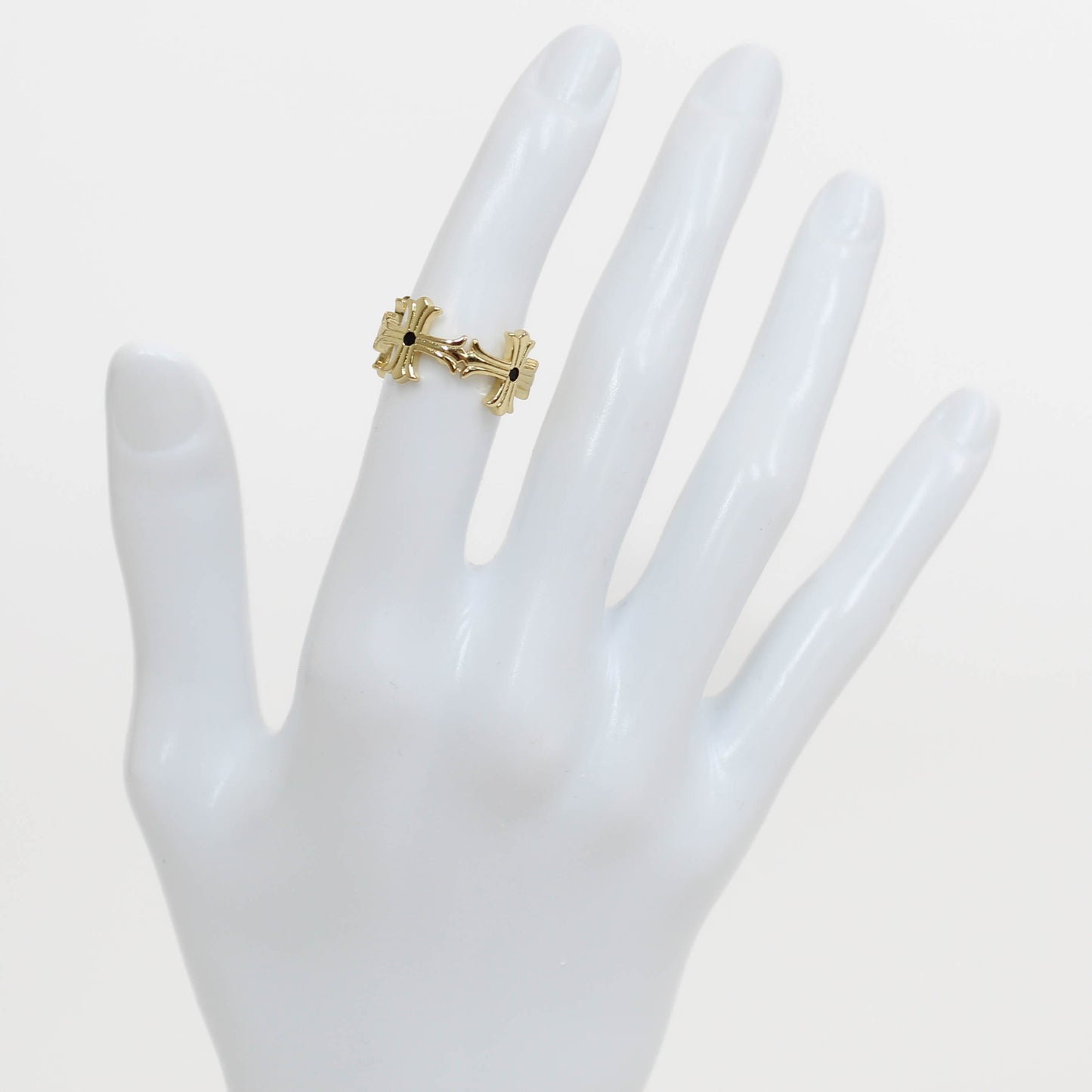 Gold textured cross ring on a white mannequin hand against a white background