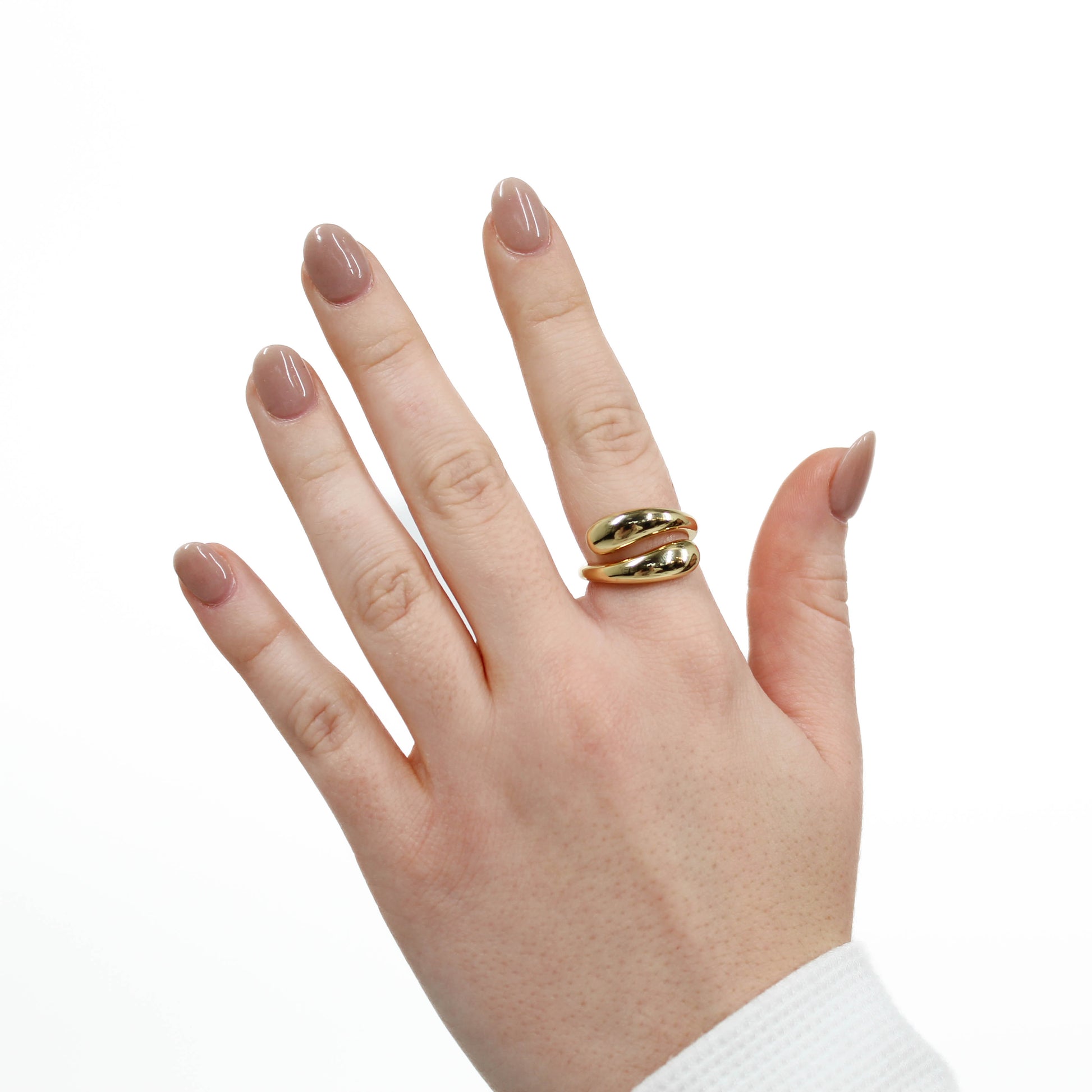 Hand wearing a gold wrap ring on a white background