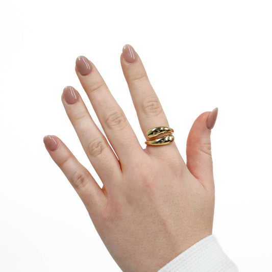 Hand wearing a gold wrap ring on a white background