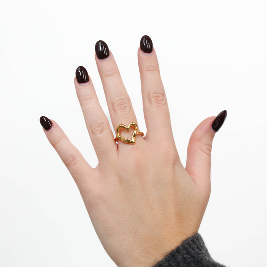 Hand wearing a gold halo heart ring on a white background