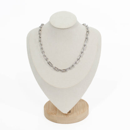 Silver chain hardware necklace on a white mannequin bust with a wooden base against a white background