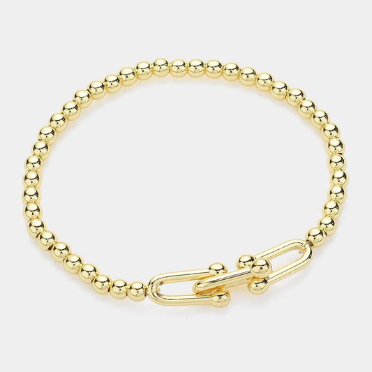Gold beaded stretch bracelet with a hardware clasp on a white background