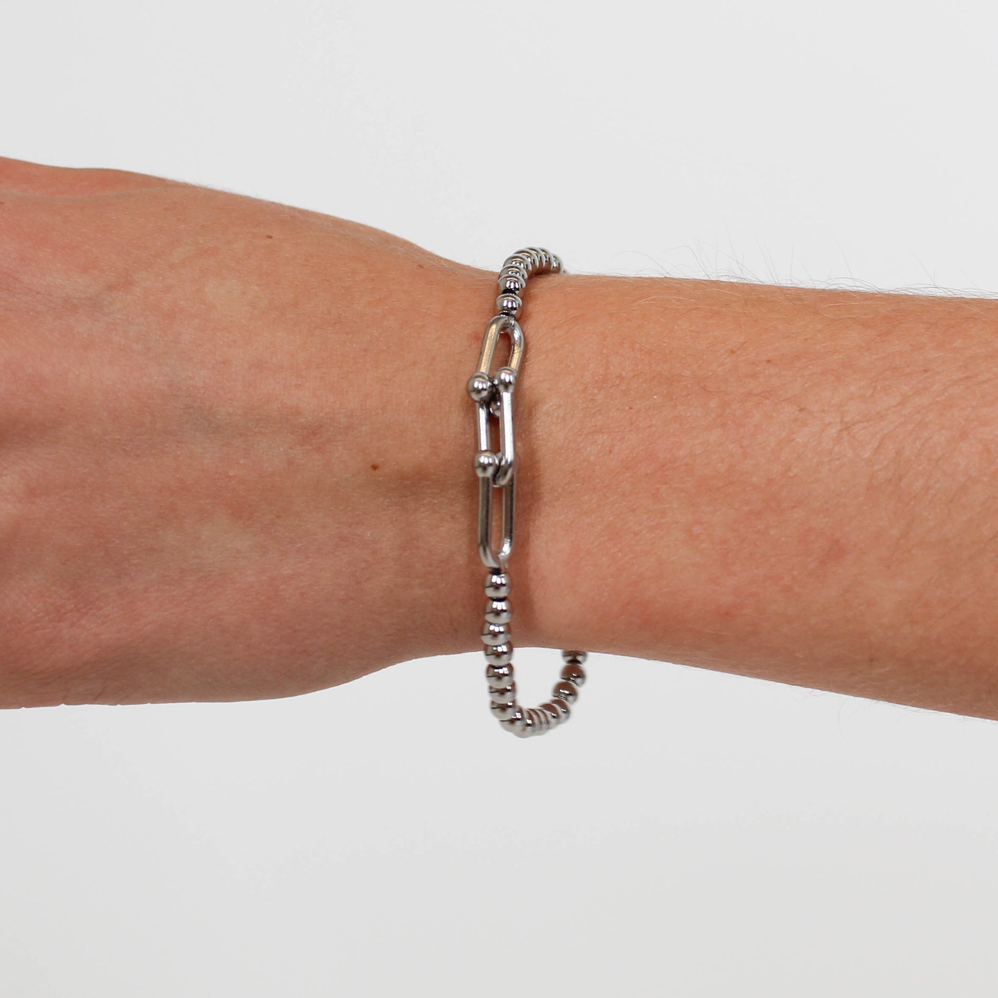 Silver chain bracelet on a wrist against a white background