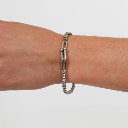 Silver chain bracelet on a wrist against a white background