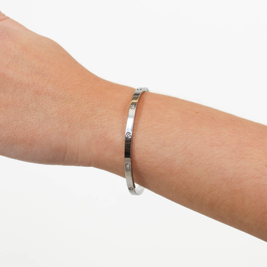 Silver bracelet on a person's wrist against a white background